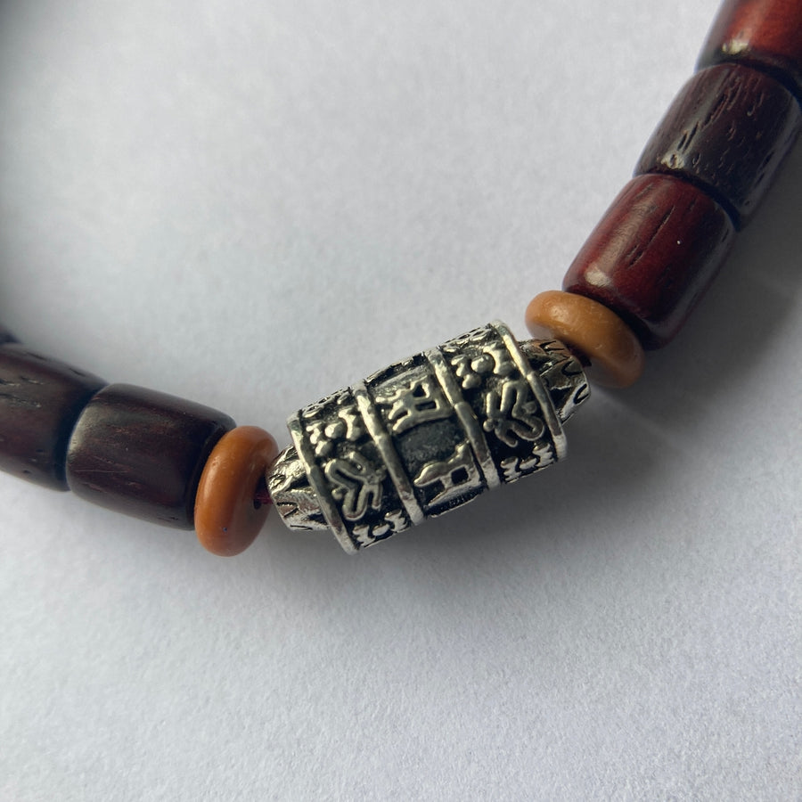Pulsera con cuentas de madera barnizada y dije cilíndrico de Molino de Oración